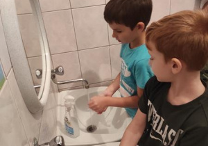 Piotr i Filip myją ręce zgodnie z instrukcją.